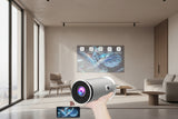 Portable projector held by a hand with features displayed on a screen in the background.